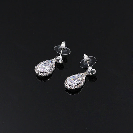 Sparkling silver-toned necklace and matching teardrop earrings set with clear stones, displayed on a black stand. - Image 3