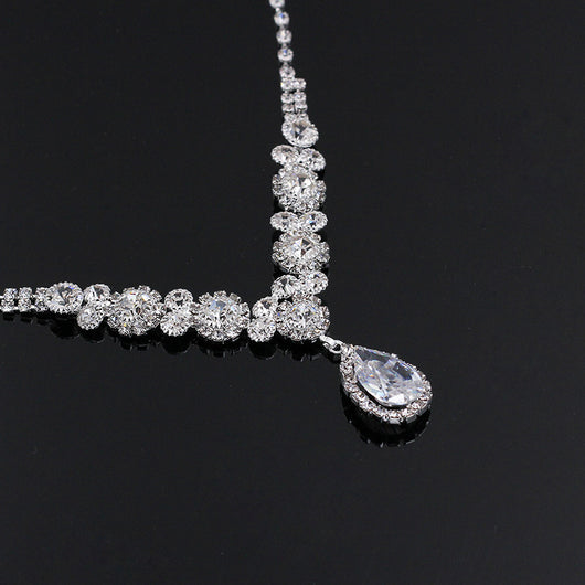 Sparkling silver-toned necklace and matching teardrop earrings set with clear stones, displayed on a black stand. - Image 5