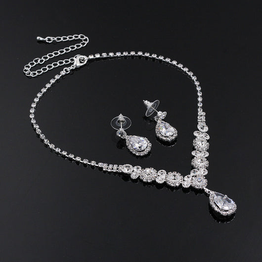 Sparkling silver-toned necklace and matching teardrop earrings set with clear stones, displayed on a black stand. - Image 4