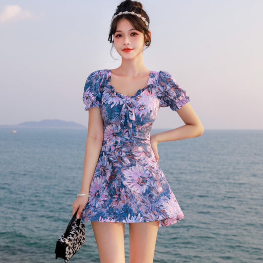 Woman in a blue and pink floral print swimsuit with puff sleeves and a square neckline, standing by the ocean. - Image 13