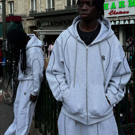 Light gray hooded tracksuit with dark gray contrast stitching, featuring a full-zip hoodie and matching loose sweatpants.