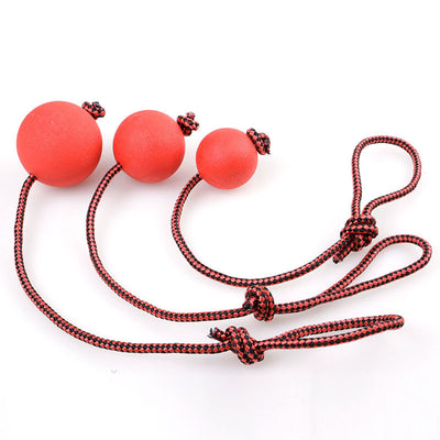 Red rubber dog ball with a red and black braided rope, featuring a knotted loop, on a light brown carpet. - Image 7
