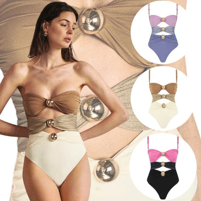 Pink, black, and dark gray color-block one-piece swimsuit with gold round buckles and a sheer black maxi skirt.