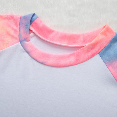 Family of four wearing matching pink, blue, and yellow tie-dye long-sleeved pajama sets in a living room. - Image 6