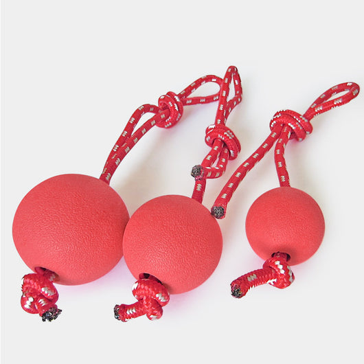 Red solid rubber elastic ball with a red and white braided rope, designed as a durable dog chew and training toy. - Image 4