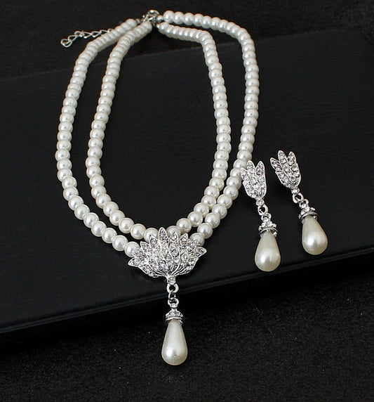 Two-strand faux pearl necklace with a rhinestone lotus pendant and matching teardrop pearl dangle earrings.