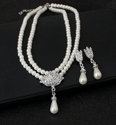 Two-strand faux pearl necklace with a rhinestone lotus pendant and matching teardrop pearl dangle earrings.