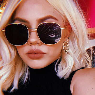 Gold metal round sunglasses with dark gray resin lenses and black temple tips on a white background.