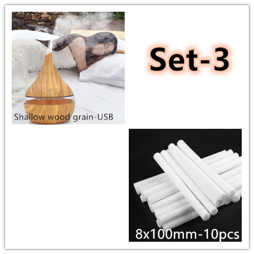 Dark wood grain LED essential oil diffuser with a blue light band and touch switch, shown with a hand operating it. Includes a bundle of 10 white filter sticks. - Image 10