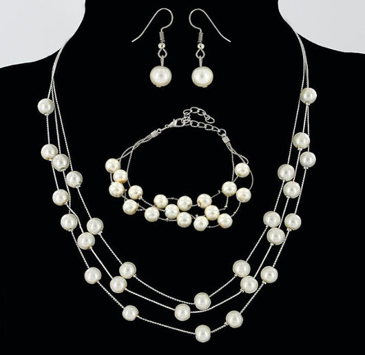 Elegant three-piece jewelry set with multi-strand pearl necklace, matching bracelet, and pearl drop earrings.