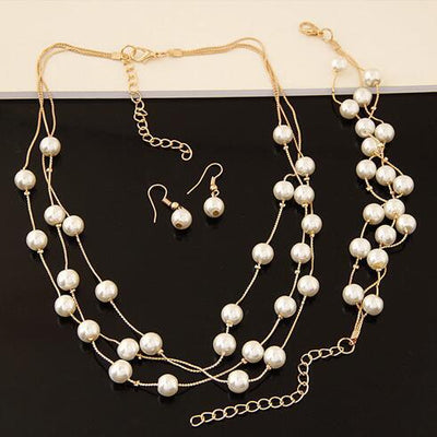 Elegant three-piece jewelry set with multi-strand pearl necklace, matching bracelet, and pearl drop earrings. - Image 3