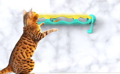 Grey tabby kitten playing with a yellow and teal wall-mounted cat toy featuring a track with rolling balls. - Image 2