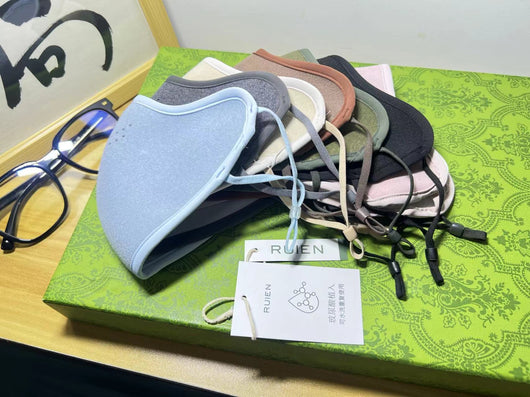 Dark gray cotton head-mounted mask with adjustable ear loops, shown in packaging on a patterned green surface. - Image 19