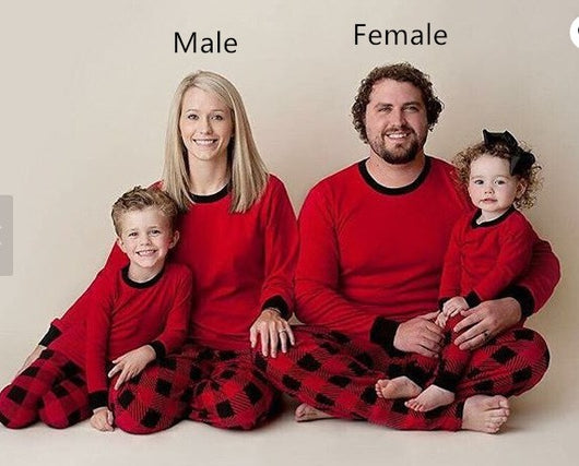 Family of four wearing matching red and black buffalo plaid Christmas pajamas, featuring solid red long-sleeve tops and plaid pants.