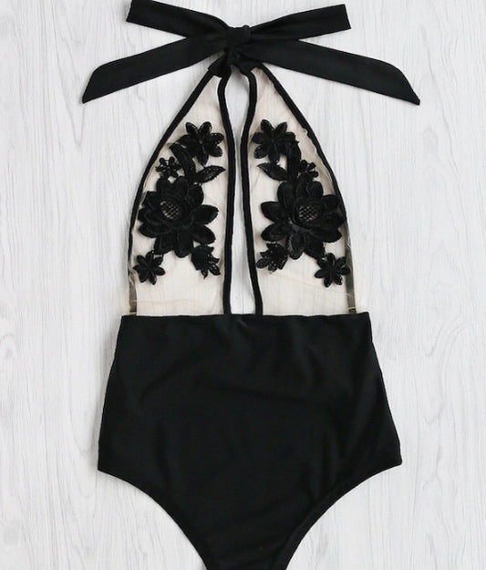 Black one-piece bikini with halter neck, sheer mesh top, and intricate black floral applique details.