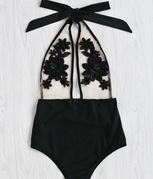 Black one-piece bikini with halter neck, sheer mesh top, and intricate black floral applique details.