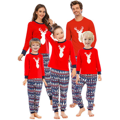 Family of five wearing matching red and navy blue Christmas pajamas with reindeer tops and fair isle pants.