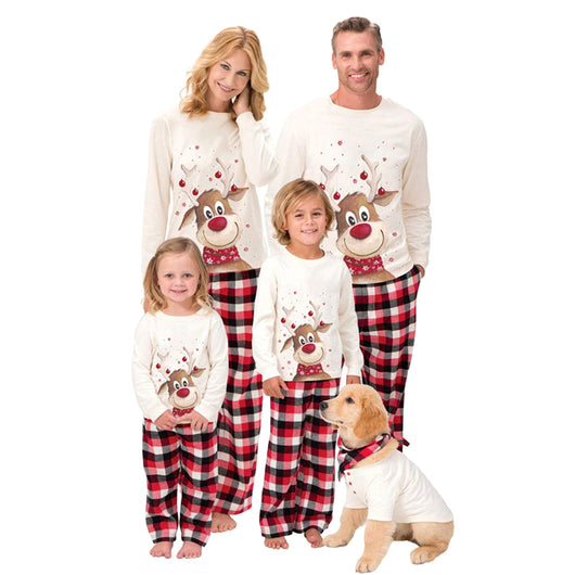 Family of four and a golden retriever puppy wearing matching cream reindeer print and red plaid Christmas pajamas.