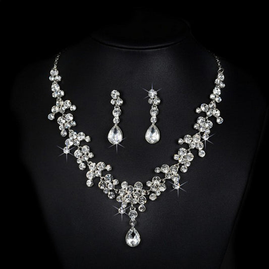 Sparkling silver-tone rhinestone necklace and matching teardrop earrings set on a black background.