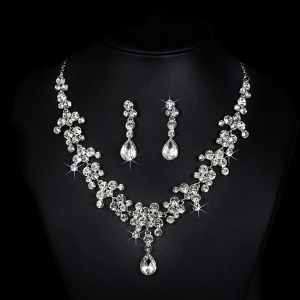 Sparkling silver-tone rhinestone necklace and matching teardrop earrings set on a black background.