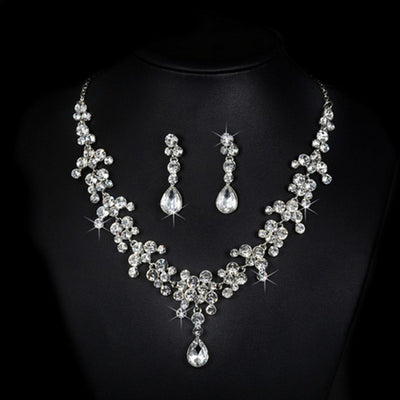 Sparkling silver-tone rhinestone necklace and matching teardrop earrings set on a black background.