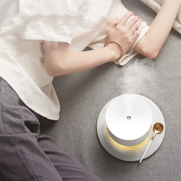 Pink cylindrical mini wireless humidifier with a clear base and a small gold mist outlet on top.