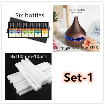 Dark wood grain LED essential oil diffuser with a blue light band and touch switch, shown with a hand operating it. Includes a bundle of 10 white filter sticks. - Image 8
