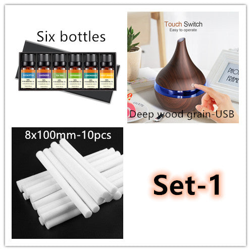 Dark wood grain LED essential oil diffuser with a blue light band and touch switch, shown with a hand operating it. Includes a bundle of 10 white filter sticks. - Image 8
