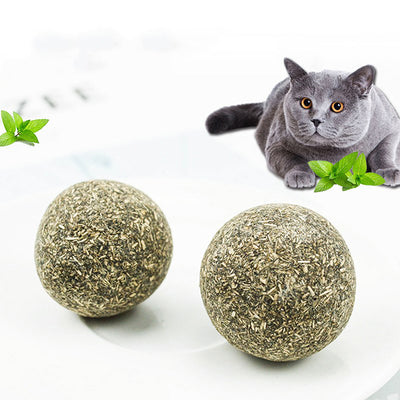 A hand holds a spherical catnip ball made of dried mint leaves and stems, light green and brown in color. - Image 4