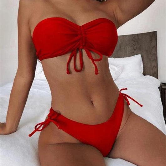 Red two-piece bikini with a strapless ruched bandeau top and matching side-tie bottoms, displayed on a white surface.