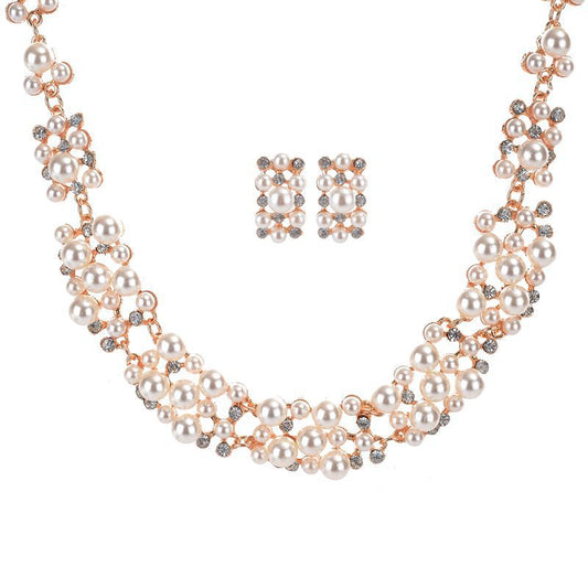Gold-toned heart-shaped necklace and dangle earrings set with clear rhinestones and faux pearls.