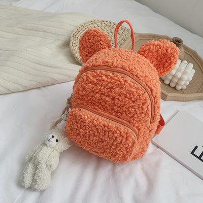 Pink fuzzy mini backpack with bear ears and a small white teddy bear keychain on a white bed. - Image 14