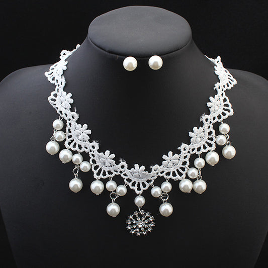 White lace choker necklace with dangling faux pearls and a central rhinestone pendant on a black jewelry bust.