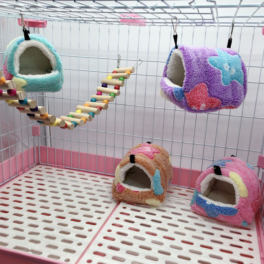 Colorful plush pet sleeping bag with purple, blue, and pink blocks, white fleece lining, and metal hooks for hanging.