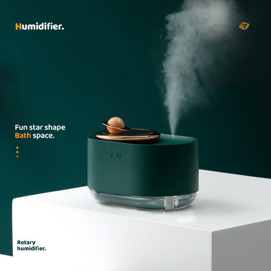 Dark green and rose gold rotating planet humidifier with a clear water tank and a wooden planet-like top. - Image 5
