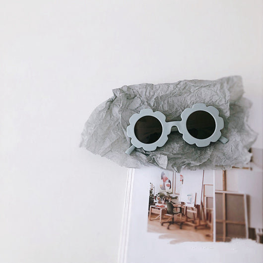 Cream flower-shaped sunglasses for babies and toddlers with dark lenses, displayed on crumpled grey paper. - Image 18