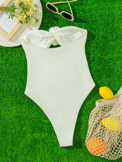 White strapless one-piece swimsuit with 3D flower details and side cut-outs, worn by a woman by an infinity pool. - Image 9