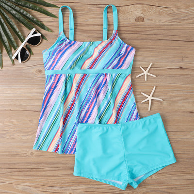 Woman in a black and white abstract print tankini top with black swim shorts on a sunny beach. - Image 19