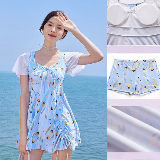 Woman in a light blue floral print swimsuit with sheer white short sleeves and a skirted bottom at the beach. - Image 3