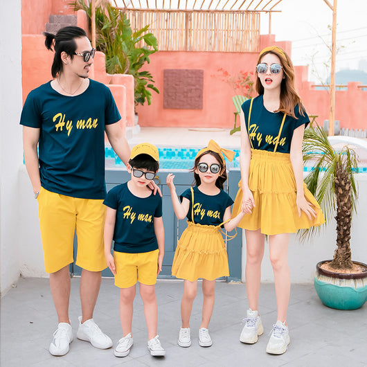 Family of four in matching dark blue short-sleeved tops with yellow text and yellow bottoms, posing outdoors. - Image 11