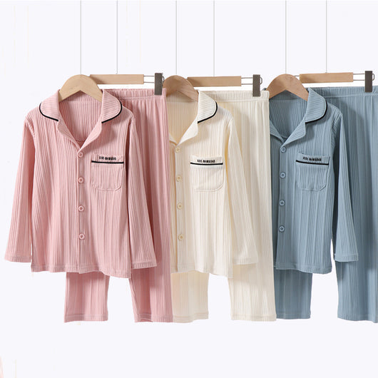 Beige ribbed cotton children's pajama set with long-sleeved lapel top and matching pants, featuring black trim.