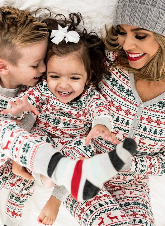 Family of four wearing matching white, red, and green fair isle Christmas pajamas with reindeer and snowflake patterns. - Image 15