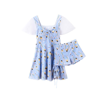 Woman in a light blue floral print swimsuit with sheer white short sleeves and a skirted bottom at the beach. - Image 11
