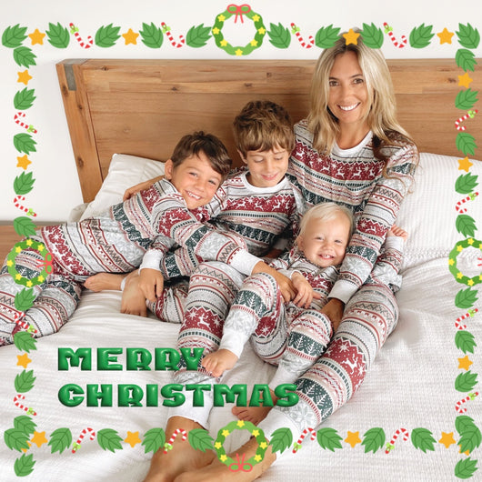 Family of four wearing matching Christmas pajamas with red, green, and grey Fair Isle reindeer and snowflake pattern.