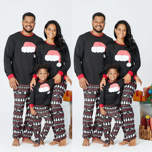 Family of three wearing matching black Christmas pajamas with Santa hat tops and reindeer fair isle pants. - Image 2