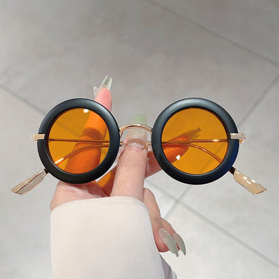 Small frame oval fashion sunglasses with black frames and vibrant orange lenses, held by a hand. - Image 8
