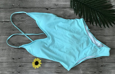 Light blue backless one-piece swimsuit with thin straps, made of polyester, laid flat on a wooden surface. - Image 5