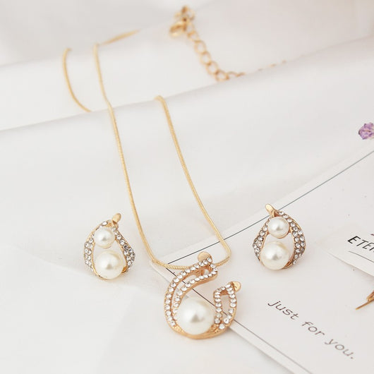 Gold-tone teardrop necklace and matching stud earrings set with white pearls and clear rhinestones, displayed on black. - Image 4