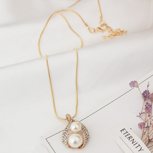 Gold-tone teardrop necklace and matching stud earrings set with white pearls and clear rhinestones, displayed on black. - Image 5