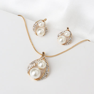 Gold-tone teardrop necklace and matching stud earrings set with white pearls and clear rhinestones, displayed on black. - Image 3